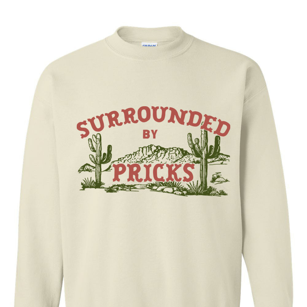 Beige sweatshirt with graphic design and text 'SURROUNDED BY PRICKS' with cacti.