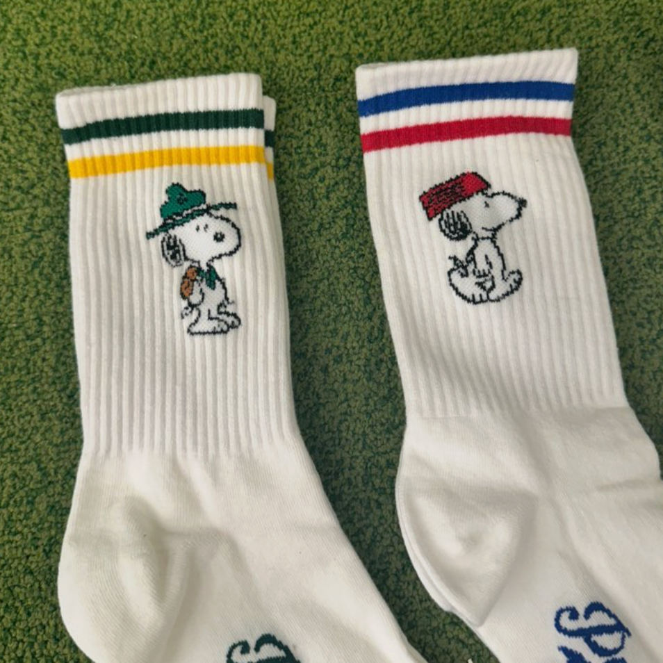 Two white socks with embroidered snoopy designs on a green background