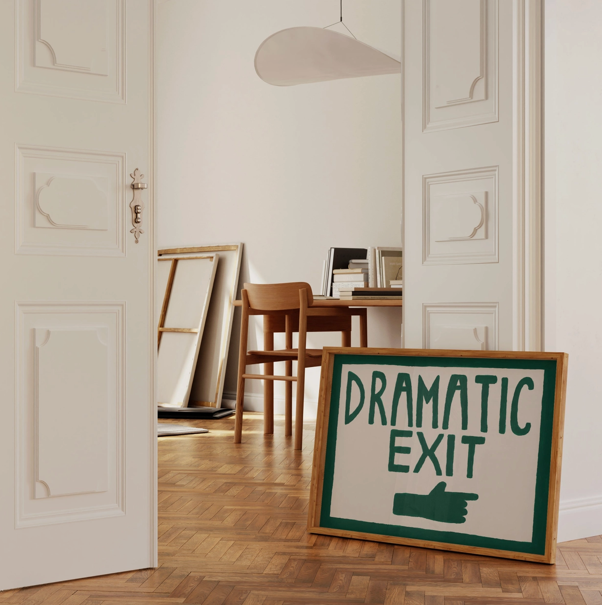Framed sign with 'Dramatic Exit' text in a room with wooden floor and white walls.