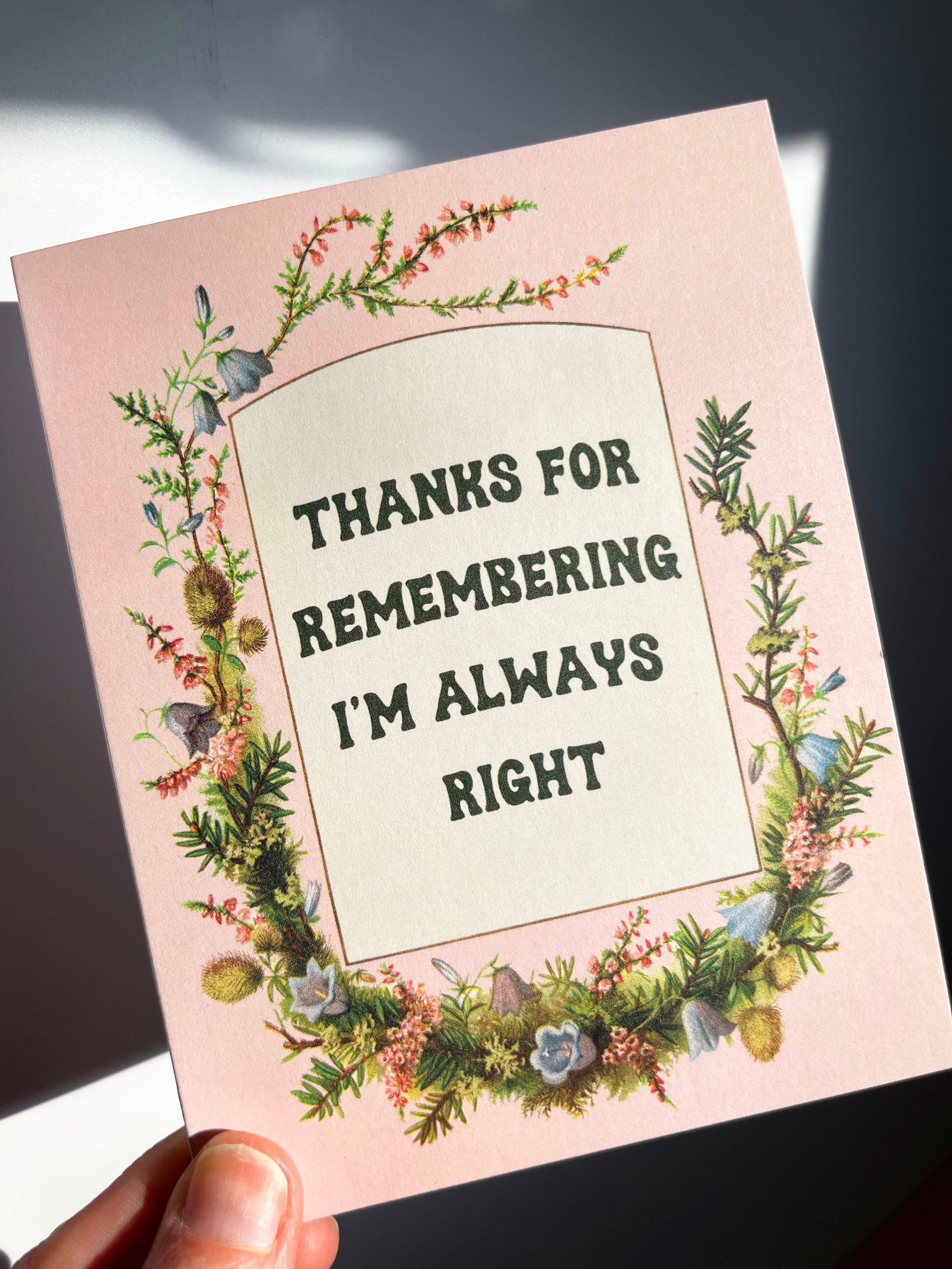 Card with floral border and text 'Thanks for remembering I'm always right' held by a hand.