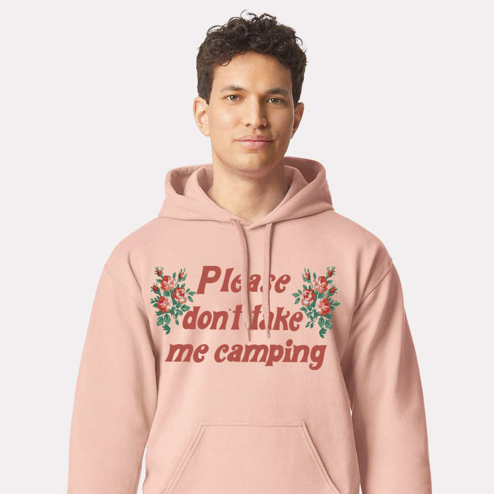 Person wearing a pink hoodie with floral text design on a plain background that says “Please don’t take me camping”