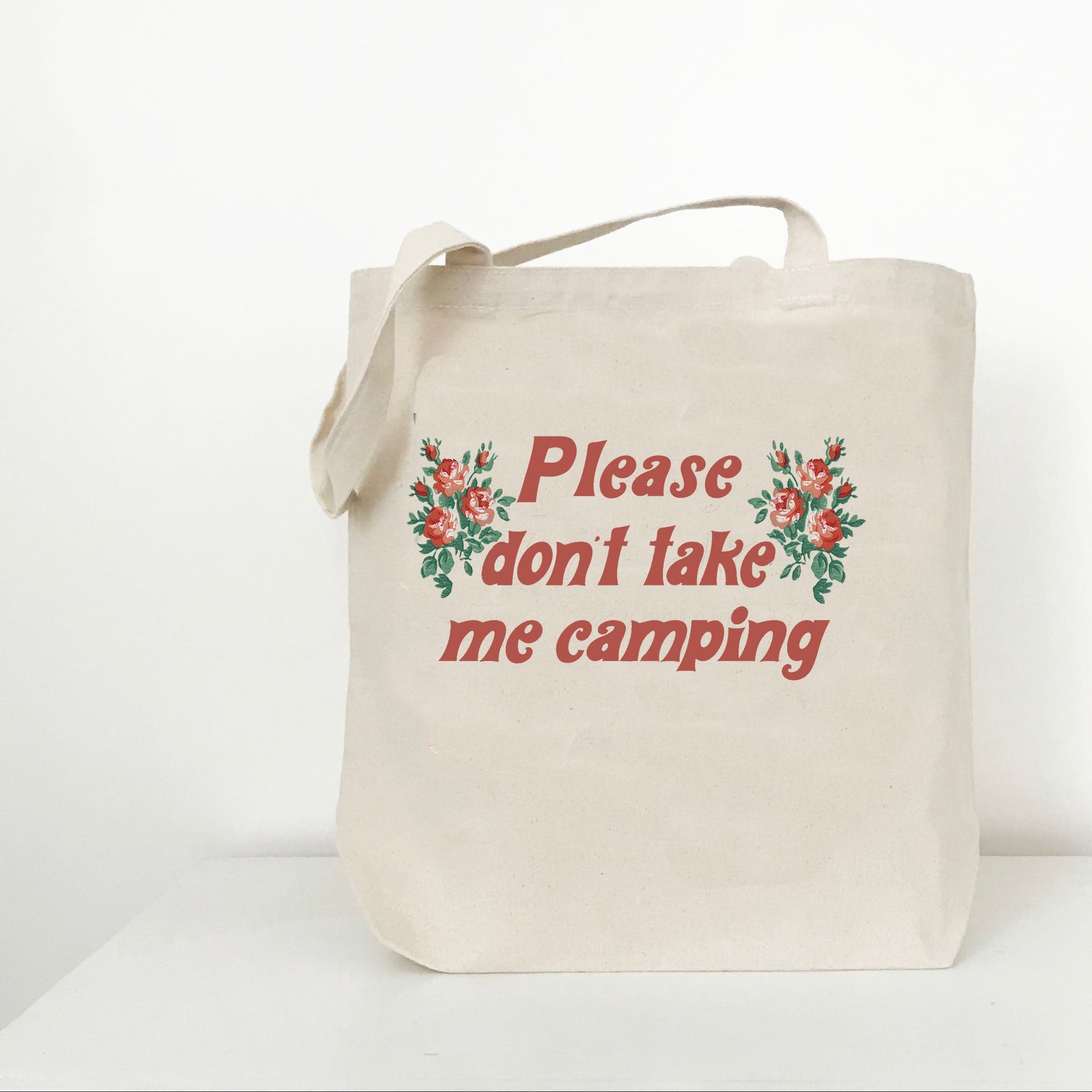 Beige tote bag with floral design and text 'Please don't take me camping' on a white background
