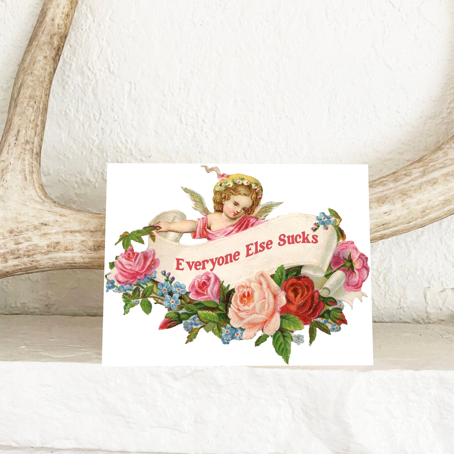 Card with angel and floral design and text 'Everyone Else Sucks' on a white background