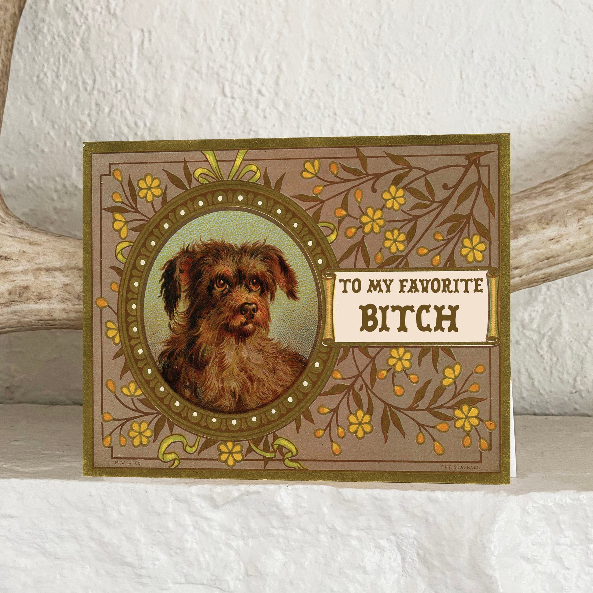 Card with a dog illustration and text 'To my favorite bitch' on a textured surface.