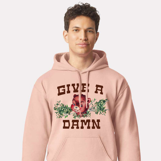 Person wearing a pink hoodie with a give a damn beaver graphic design and text 
