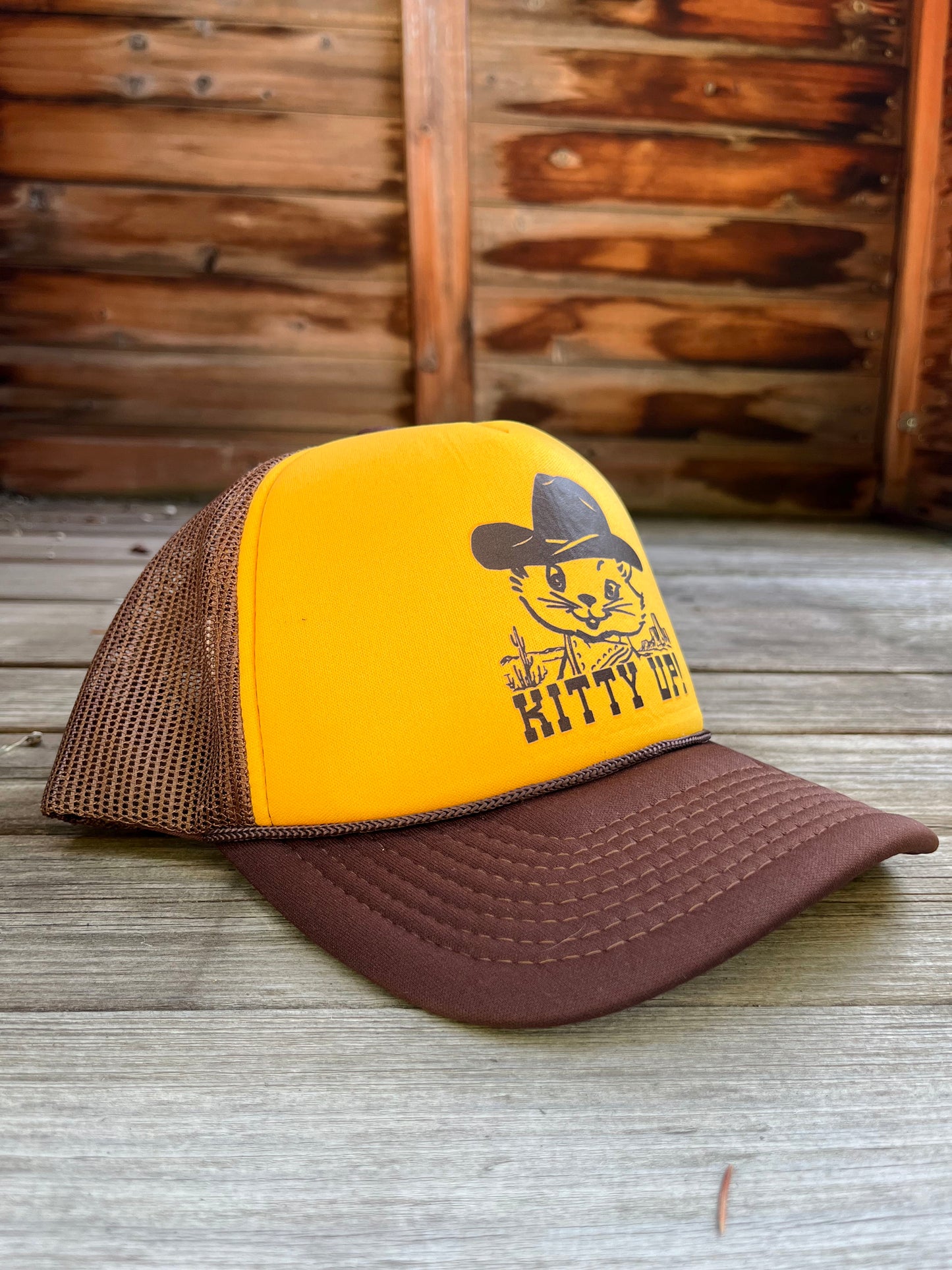 Yellow and brown trucker hat with a cat graphic and 'Kitty Up!' text.