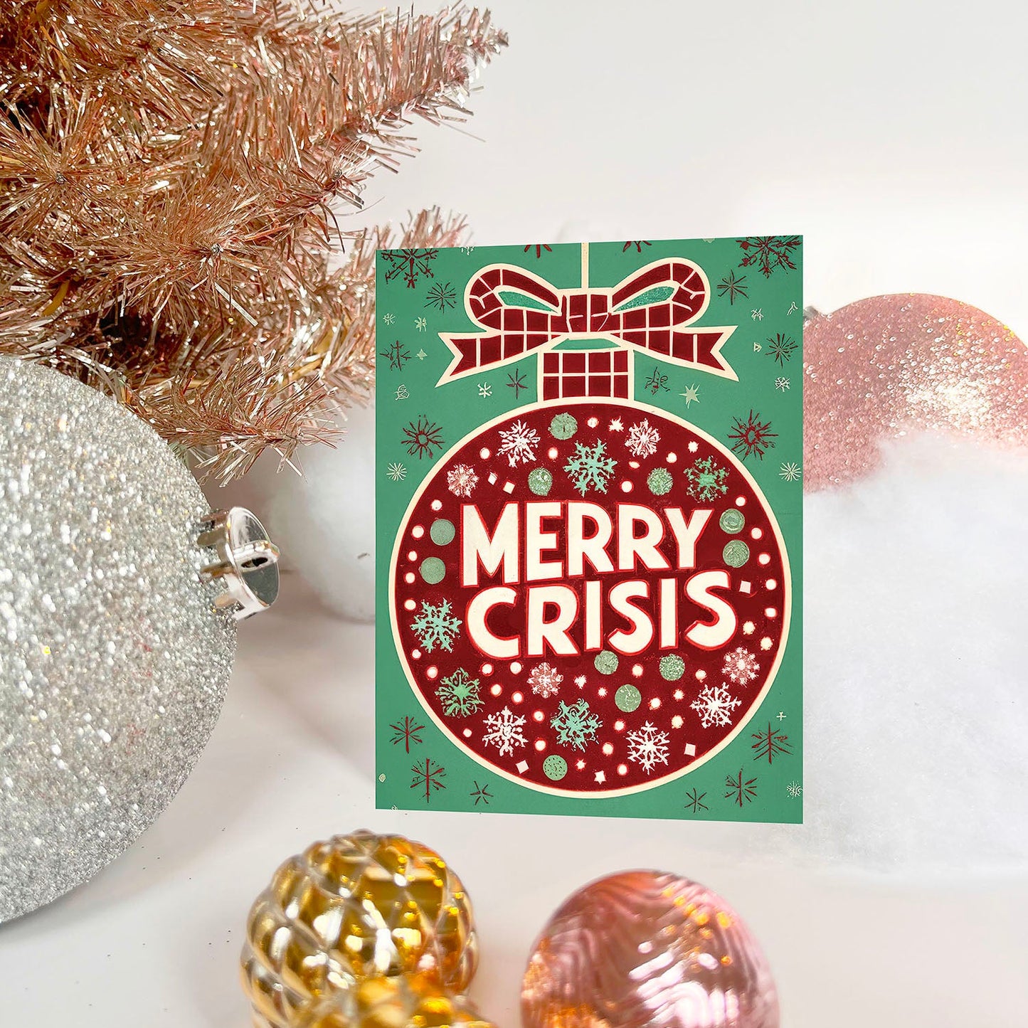 Red ornament on a green background with “Merry Crisis” text and snowflakes.