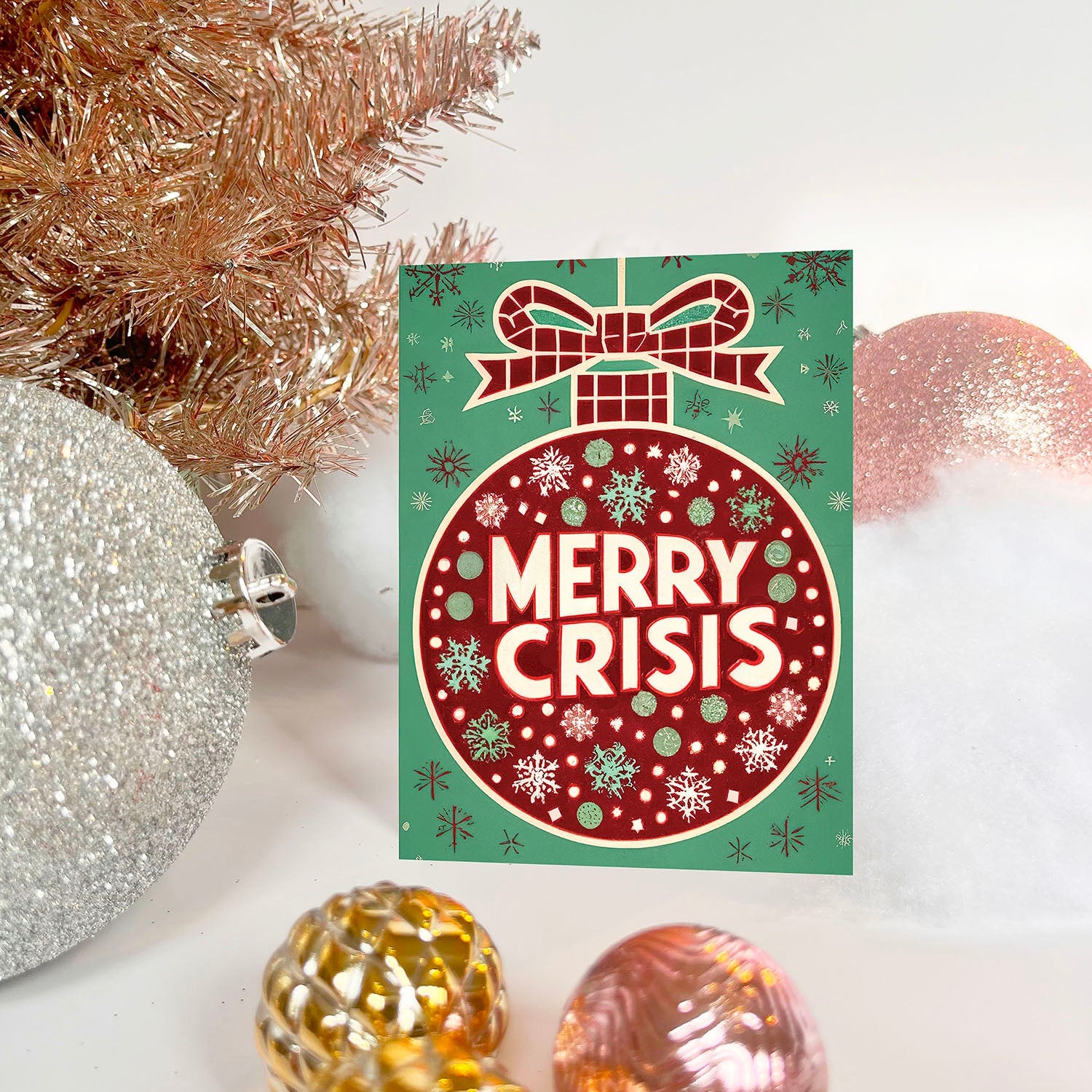 Red ornament on a green background with “Merry Crisis” text and snowflakes.