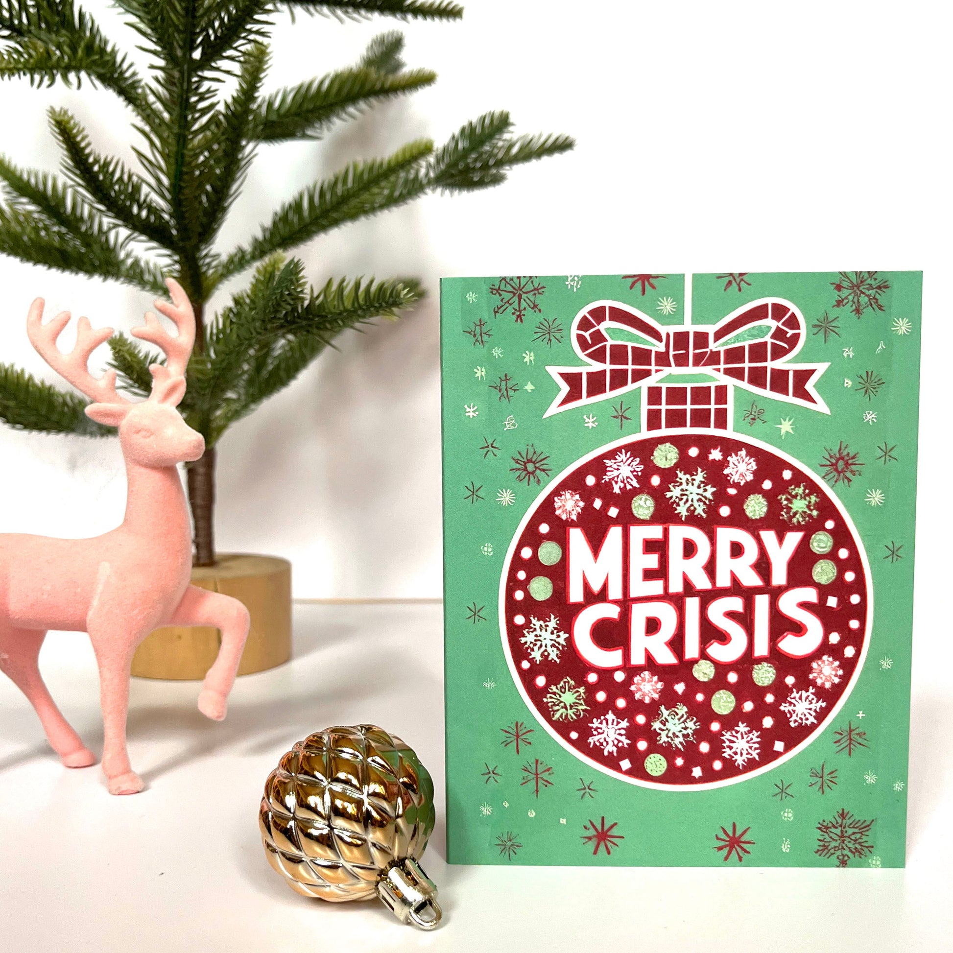 Red ornament on a green background with “Merry Crisis” text and snowflakes.