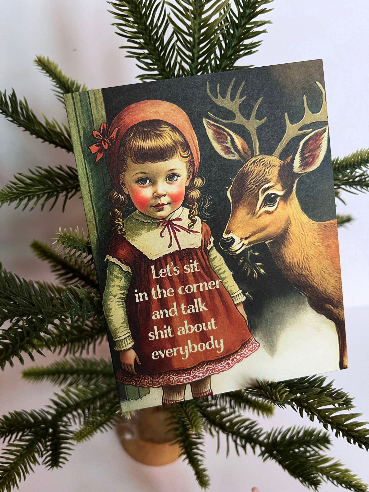 A greeting card featuring a vintage style illustration of a girl with a deer, with the text 'Let's sit in the corner and talk shit about everybody”