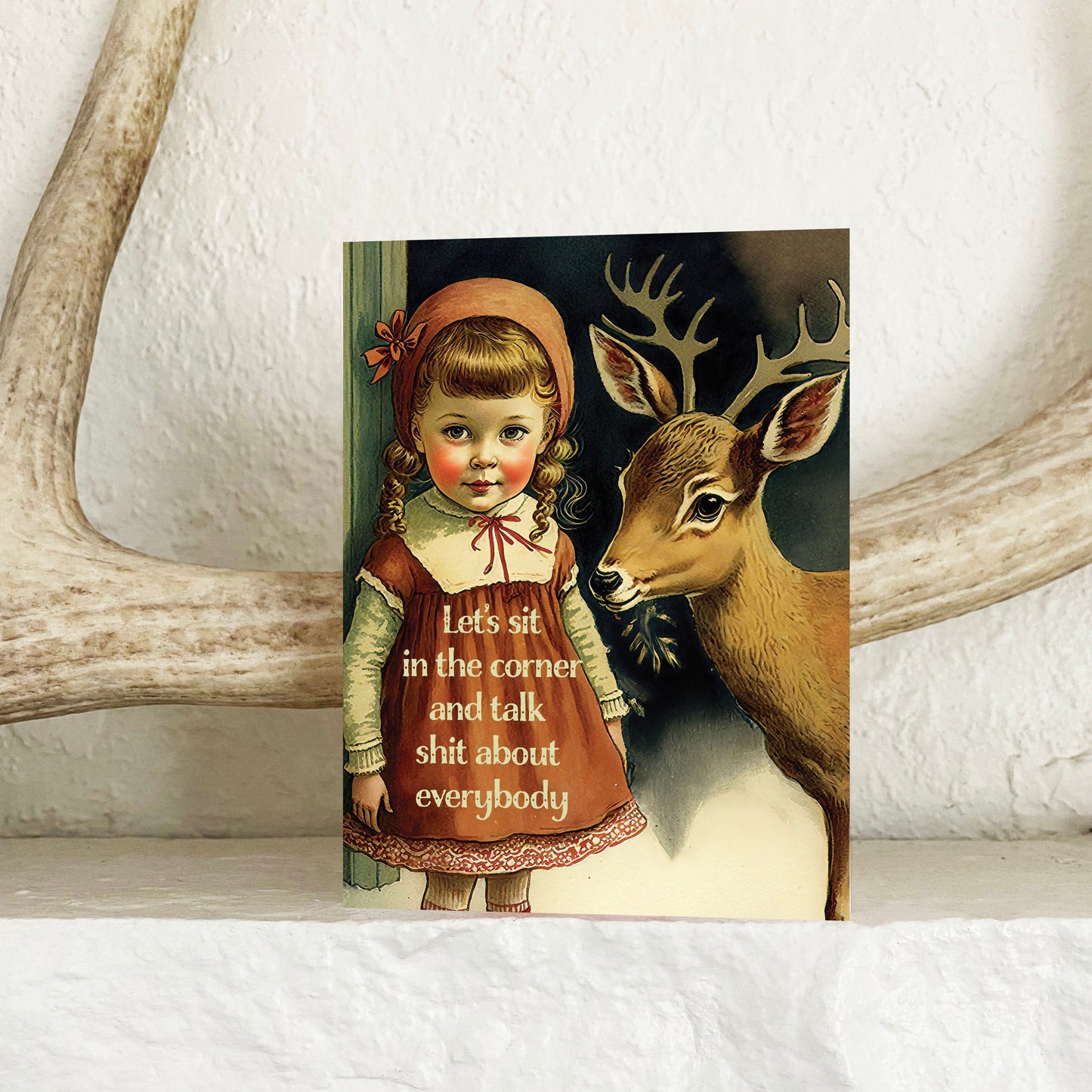 A greeting card featuring a vintage style illustration of a girl with a deer, with the text 'Let's sit in the corner and talk shit about everybody”
